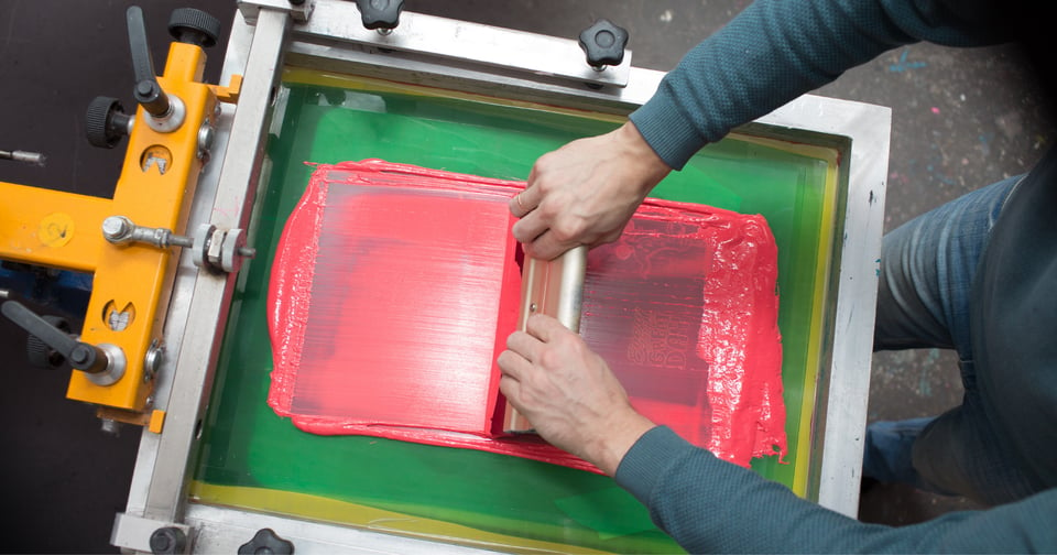 Close up of hands spreading ink on a screen printer