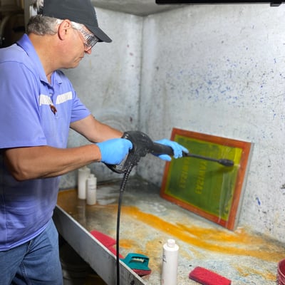 Man cleaning a screen with a spray machine