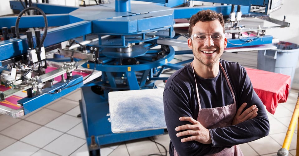 Man smiling in print shop with equipment