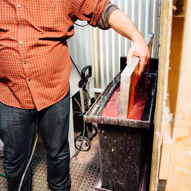 Man dipping a screen into a dip tank