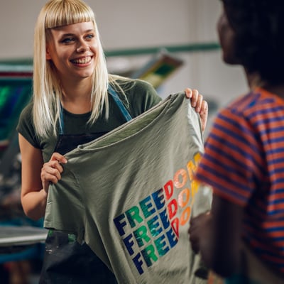 Woman holding a printed shirt in her shop